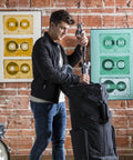 Man using Heavy Duty Rolling Drum Cart With Removable Nylon Gear Bag And Tough Steel Frame to store stage gear.