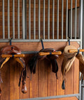 Portable Saddle T Hanger For Car And Trailer Heavy Duty Headrest Saddle Rack Organizer holding leather saddles in barn