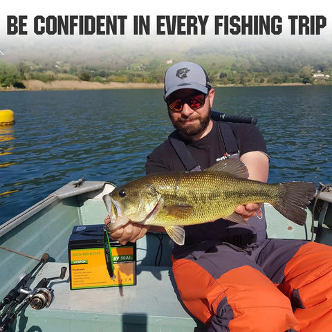 Angler holding fish on boat with Beefy 12V 50Ah LiFePO4 Trolling Battery With 4A Smart Charger beside, lake in background