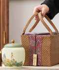 Top Shelf Ceramic Tea Tin With Woven Rattan Travel Case, Stunning Mountain Landscape Design, Go To Stash Jar For Loose Leaf Tea Or Specialty Coffee Beans In Slate Blue beside a wicker pouch.