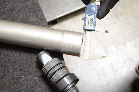 Astro Pneumatic exhaust pipe stretcher kit, metallic, close-up view with digital caliper measuring pipe