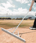 Person using Aluminum Maintenance Rake With Adjustable 66 To 98 Inch Handle on a baseball field; 36 inch head, rustproof aluminum.