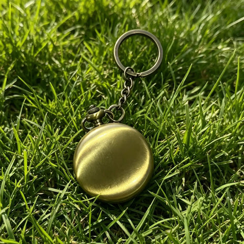 Brass compass with keychain in grass, part of Custom Damascus Steel Folding Knife With Wooden Handle And Separate Compass In Wooden Gift Box Go To EDC Outdoor Knife For Camping Fishing Hunting And Survival Perfect Fathers Day Gift For Dad Or Boyfriend