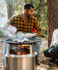 Man cooking on Large Cast Iron Grill Top For Bonfire And Yukon Fire Pit Outdoor Cooking Surface Seventeen And Three Quarters Inch 17 Lbs