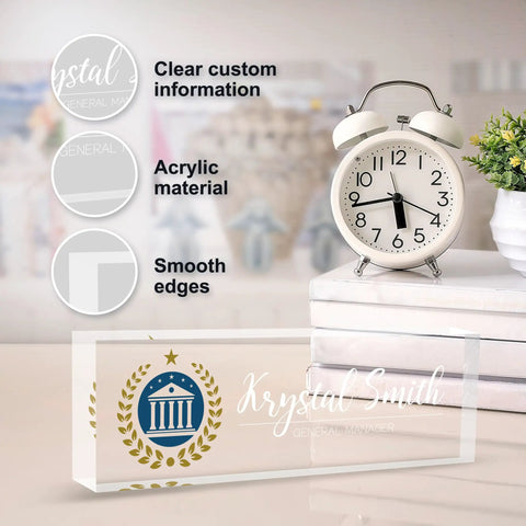 Clear acrylic Fully Customizable Desk Name Plate With Logo Upload, smooth edges, next to a white clock and plant.