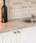 Premium Champagne Bronze Cabinet Knobs And Drawer Pulls 1-1/5 Inch 10 Pack on white cabinetry with stone countertop and black bottle.
