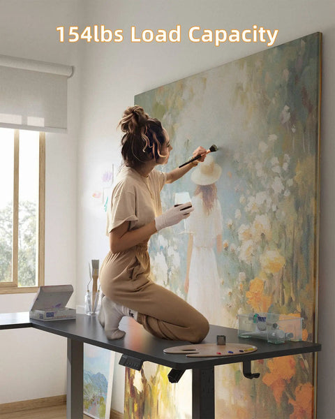 Yihayo 55 Inch L Shaped Electric Standing Desk in use, supporting 154lbs, with artist painting on top.