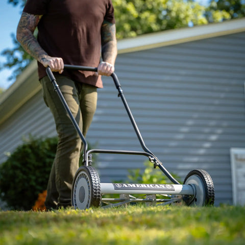 Person using the 18-Inch Push Reel Lawn Mower With 5 Blades, Heat-Treated Alloy Steel Blades, Scissor-Cut Action, in a garden.