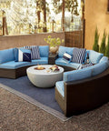 Outdoor patio with circular wicker sectionals and blue cushions, surrounding a modern fire pit table.