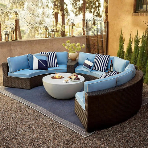 Outdoor patio with circular wicker sectionals and blue cushions, surrounding a modern fire pit table.