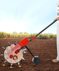Person using walk behind garden seeder spreader and planter with 10 nozzles for precise sowing and fertilizer application in a field.