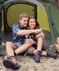 Couple sitting in front of 4 Person Easy Pop Up Tent With Automatic Setup No Fuss Waterproof Family Camping Tent With Skylight And Removable Rainfly Two Doors 190T Polyester PU 3000 Coated For Rainy Days And Sunny Campouts