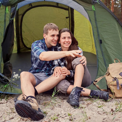 Couple sitting in front of 4 Person Easy Pop Up Tent With Automatic Setup No Fuss Waterproof Family Camping Tent With Skylight And Removable Rainfly Two Doors 190T Polyester PU 3000 Coated For Rainy Days And Sunny Campouts