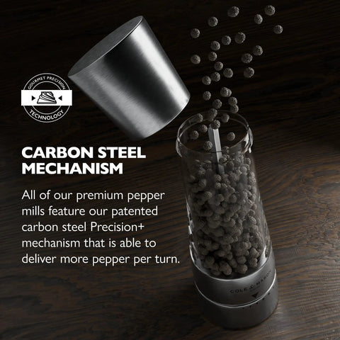 Close-up of stainless steel pepper grinder showing carbon steel mechanism, pepper pouring out. Pepper Grinder With Adjustable Six Level Grind.