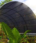 70 Percent Shade Cloth 20x20 Ft HDPE Mesh Tarp With Reinforced Grommets For Outdoor Shade Perfect For Greenhouses Gardens Patios Pergolas Chicken Coops And Outdoor Areas Breathable UV Blocking Sun Shade Net installed over a garden area.