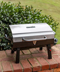 Stainless steel Single Burner Portable Propane Grill With Piezo Ignition on brick surface, ready for outdoor cooking.