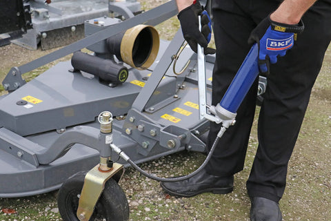 Lincoln 1147 lever-action manual grease gun with blue handle and 18-inch whip hose connected to heavy machinery