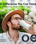 Person drinking from grab-and-go portable alkaline water filter pouch in bottle, high pH water alkalizer, outdoors.