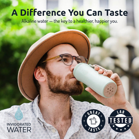 Person drinking from grab-and-go portable alkaline water filter pouch in bottle, high pH water alkalizer, outdoors.