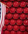 American flag in front of a background wall of red fire extinguisher bottoms.