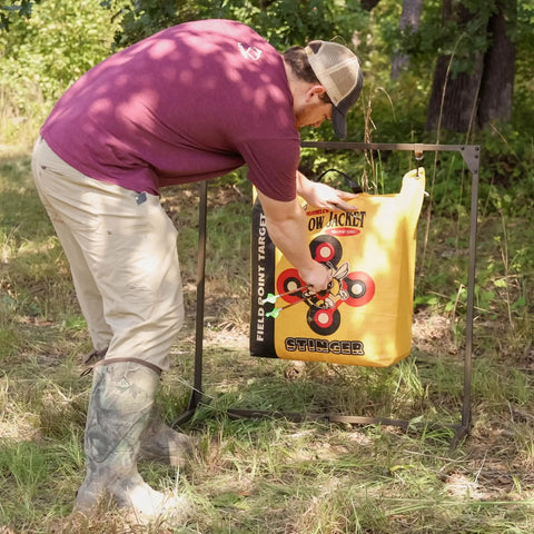 Man adjusting a bag target on a Bag Target Stand for Indoor and Outdoor Archery Practice Durable Adjustable Bag Holder in a forest