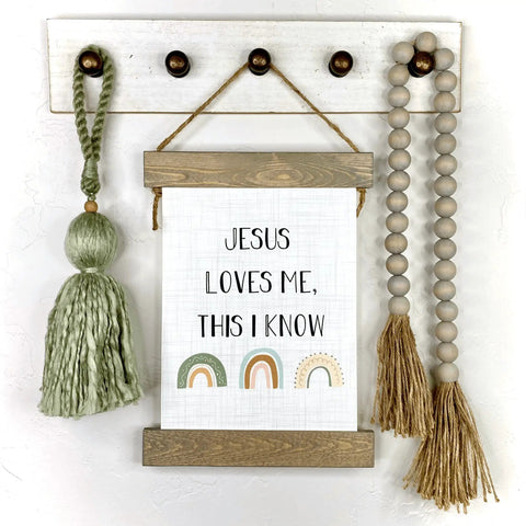 Jesus Loves Me This I Know Hanging Canvas For Kids Boho Rainbow Nursery Decor on wall with green tassel and beads