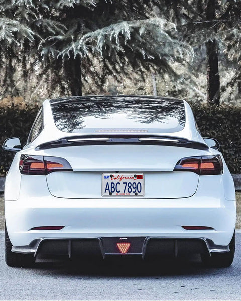 Rear view of a white Tesla with Tesla Model 3 And Model Y Rear License Plate Holder Bracket Frame With Screws Caps And Backseat Air Vent Cover Replacement Kit 109684400B Direct Fit Easy Install Now installed.