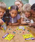 Kids using magnifying glasses to inspect the Awesome 25 Piece Rock and Mineral Kit for Kids Ages 6 to 12 STEM Geology Toy Set with Real Rocks Gemstones and Crystals for Hands On Science Discovery and Learning Perfect Starter Geology Kit for Classroom Home School Projects.