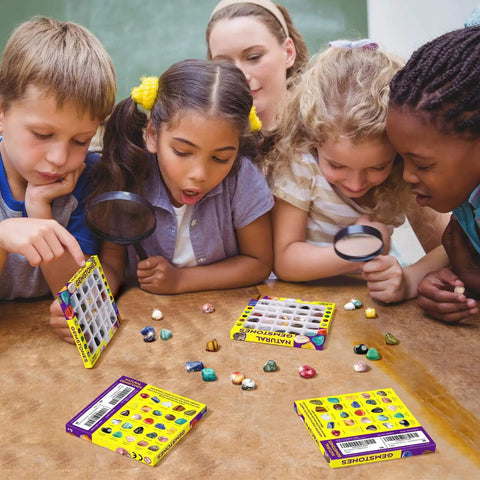 Kids using magnifying glasses to inspect the Awesome 25 Piece Rock and Mineral Kit for Kids Ages 6 to 12 STEM Geology Toy Set with Real Rocks Gemstones and Crystals for Hands On Science Discovery and Learning Perfect Starter Geology Kit for Classroom Home School Projects.