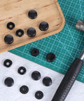 Top view of Black License Plate Screw Cap Kit With Eight Caps For Frame Bolts, universal fit, and installation tool on grid mat