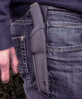 Person with Carbon Steel Fixed Blade Bushcraft Knife with Sheath on belt, black handle visible, outdoor setting