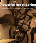 Heavy Duty Double Arm Retractable Air Hose Reel 50 Foot Reach Half Inch Steel Hybrid Core mounted on wall next to bicycles.