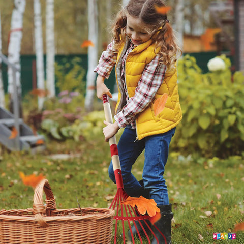 Child using red rake from Kids Garden Tool Set 4 Piece Shovel Rake Hoe Leaf Rake Wooden Gardening Tools For Kids