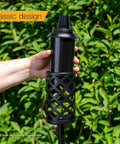 Hand holding 16 Ounce Torch Replacement Canisters 4 Pack Wide Mouth Metal With Snuffer Cap Attached Easy Fill Opening Compatible With Tiki Torches Includes Wicks For Outdoor Lighting.
