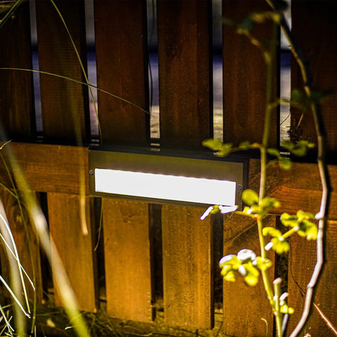 Low Voltage Outdoor Step Lights Kit 12V AC Landscape Stair Lighting 8 Pack, 6W LED Deck Lights With 122 Lumens, 3000K Warm White, shown mounted on a wooden fence at night, highlighting garden foliage.