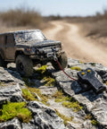 Premium Electric Rc Winch For 10 Scale Crawlers With Smooth Spool Function And Sturdy Metal Build For Steep Cliffs And Tough Wilderness Runs attached to rc vehicle on rocky terrain.
