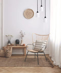Minimalist room with wicker chair, indoor plants, and pendant lights hanging from ceiling.