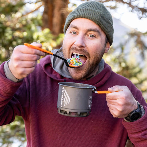 Person eating cereal with TrailSpoon Extendable Backpacking Spoon With Silicone Edge For Pots Reach Inside Cookware During Camping Trips And Dehydrated Meals Long Ten Inch Reach Three Position Locking Handle Your Go To Ultralight Utensil.