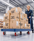 Woman pushing a cart with boxes labeled 'Heavy Duty Gearbox Assembly', showcasing Heavy Duty 3 Inch Caster Wheels Set Of 4 With Thick Steel Brackets And Total Lock Brakes Rated Up To 1410 Lbs Capacity Built Tough As Nails For No Sweat Loadin Tasks.