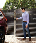 Man operating Dual Sided Lockable Magnetic Gate Latch Matte Black on modern slatted fence near a vehicle.