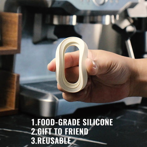 Hand holding 58mm Silicone Steam Ring Set Of 2 for Breville and Sage espresso machines BES900XL BES920XL in front of machine