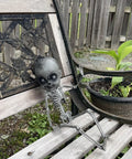 18 Inch Creepy Skeleton Boy Doll With Movable Joints sitting on wooden bench in garden, durable all weather plastic