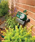 Extra Valve For Hose Faucet Yard Watering Kit 58911 attached to outdoor brick wall with garden plants below
