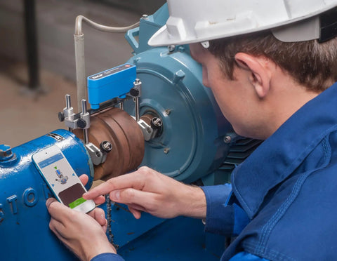 Technician using Pro Grade Shaft Alignment Tool TKSA 11 For Precise Drive System Alignment with smartphone app support on machinery.