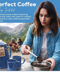 Durable Classic Enamel 12 Cup Coffee Percolator with two mugs for camping and outdoor brewing next to person scooping beans.
