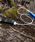Wizard Pro V3 XHP50 Warm USB Magnetic Headlamp with 2300 Lumens on mossy log connected to blue USB charger