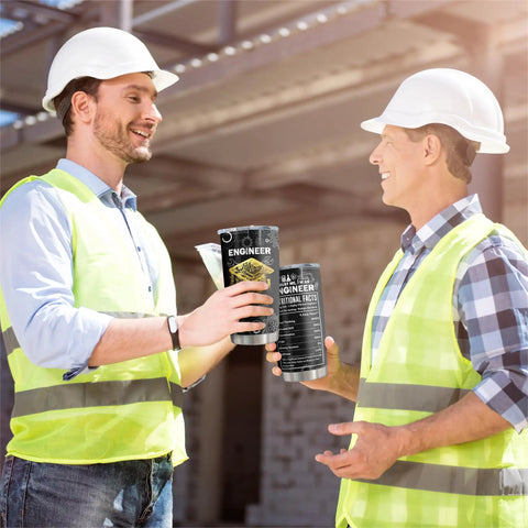 Two engineers holding Engineer Gifts Tumbler 20Oz for Mechanical Engineers, wearing hard hats and vests on a construction site.
