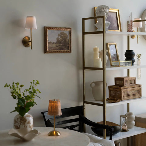 BSFHKLA Cordless Rechargeable Wall Sconce with Scalloped Fabric Shade and Remote, Brass Finish, USB, Dimmable LED Lighting(WhiteVelvet) above a shelf.