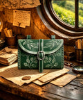 Totally Sick Medieval Renaissance Belt Bag For Women Featuring Green Floral Embossed PU Leather Waist Pouch With Antique Ring Buckle on desk.