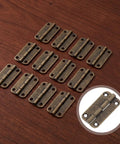 Antique Bronze Small Hinges for Wooden Boxes and Jewelry Cabinets 1.38x0.71 Inch Four Hole Mount displayed on wood surface